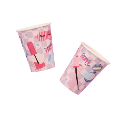Dois copos de papel decorados com imagens de batons e acessórios de maquilhagem sobre fundo lilás xadrez.