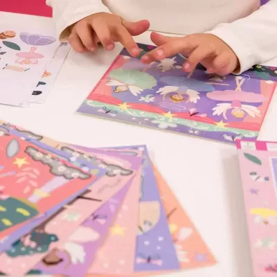 Mãos a mexer em cartões ilustrados coloridos sobre mesa branca