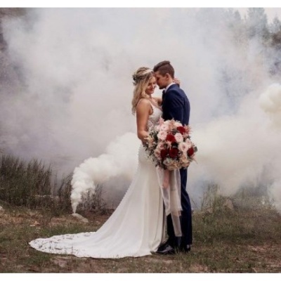 Casal de noivos abraçados em campo com nevoeiro branco ao fundo