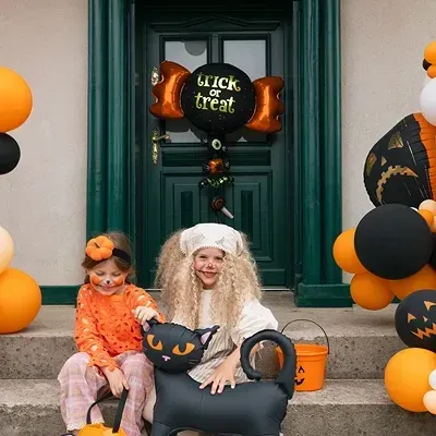 Crianças em degraus com decoração de Halloween e balões laranja e pretos