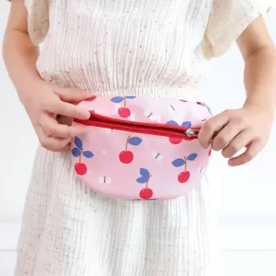 Mochila de cintura rosa com padrão de cerejas e fecho vermelho