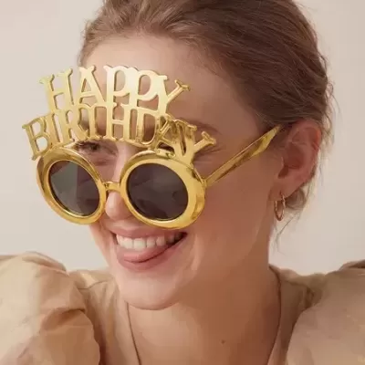 Óculos dourados de festa com a frase HAPPY BIRTHDAY usados por mulher