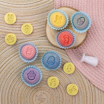 Carimbos coloridos de motivos infantis em silicone com cabo branco, sobre tapete de corda e chapéu rosa