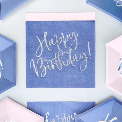 Guardanapos de papel azul e rosa com texto Happy Birthday! em caligrafia prateada.