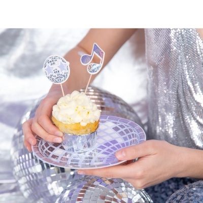 Pessoa segurando cupcake com decoração de bola discoteca e nota musical em prato prateado