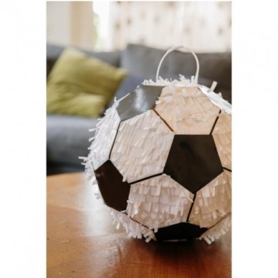 Piñata bola de futebol preto e branco em papel com franjas sobre mesa de madeira