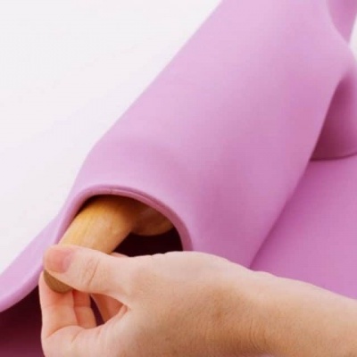 Tapete de silicone rosa enrolado em rolo de madeira com mão segurando extremidade