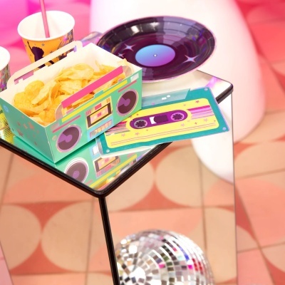 Caixa de papel e copos coloridos com batatas fritas em mesa espelhada e disco espelho no chão