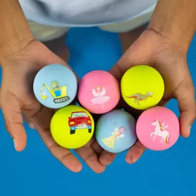 Seis bolas coloridas com desenhos infantis seguradas pelas mãos de uma criança