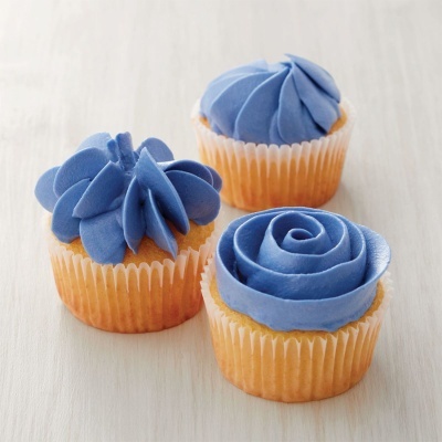Três cupcakes com cobertura azul em diferentes padrões sobre superfície clara