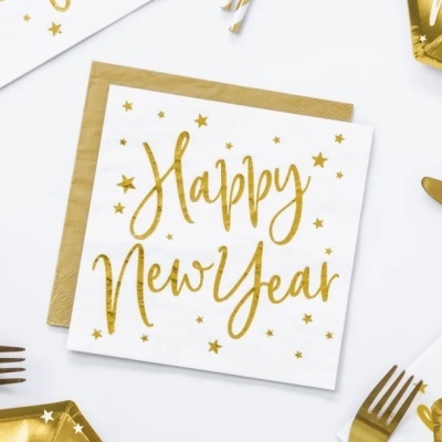 Guardanapo branco com texto dourado 'Happy New Year' e estrelas, sobre papel castanho, com talheres dourados à volta