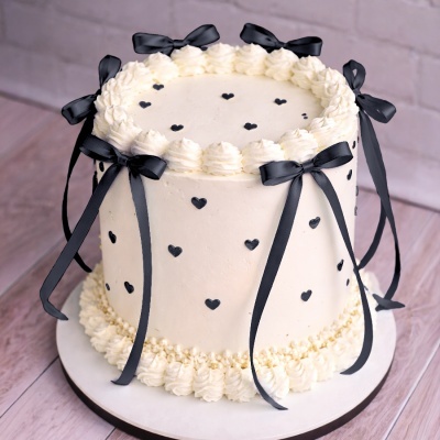 Bolo redondo decorado com chantilly branco e corações pretos