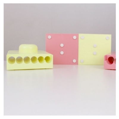 Tijolos de montar de plástico amarelo e rosa com texturas, sobre superfície branca