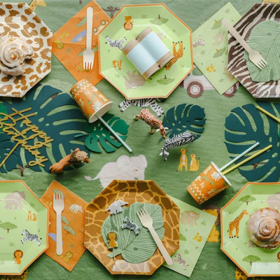 Mesa decorada para festa infantil com tema de animais da selva em papel descartável e decoração verde e laranja