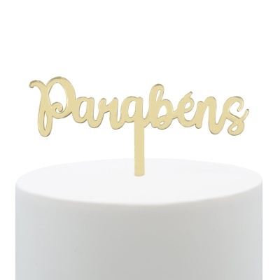 Topo de bolo dourado com a palavra Parabéns em fonte cursiva sobre bolo branco