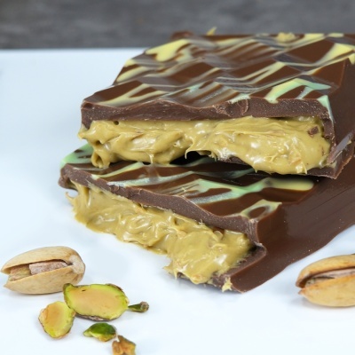 Barra de chocolate com recheio de pistache e pistáchios ao lado