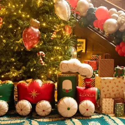 Comboio insuflável de Natal com decoração diante de árvore de Natal e presentes coloridos.