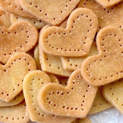 Biscoitos em forma de coração dourados com pequenos furos.