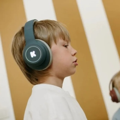 Criança com auscultadores azuis escuros com símbolo K branco na lateral