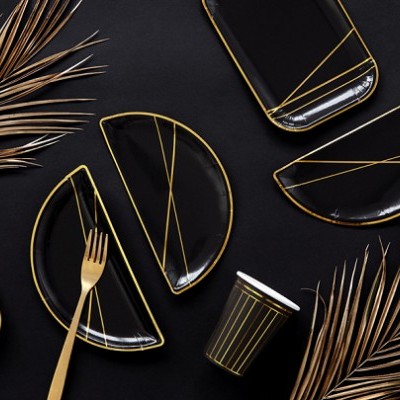 Conjunto de loiça preta e dourada com folhas decorativas secas