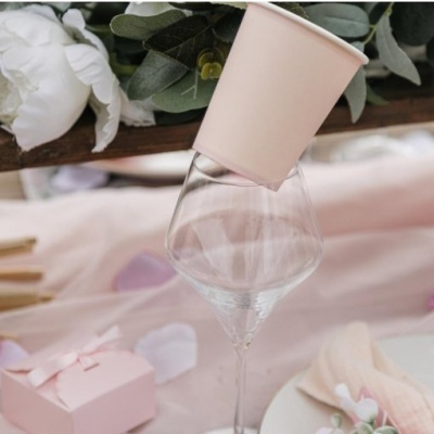 Copo descartável rosa claro sobre uma taça de vidro com decoração floral em fundo