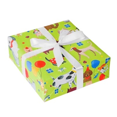 Caixa embrulhada em papel de dentro verde com desenhos de cães e balões e laço branco.