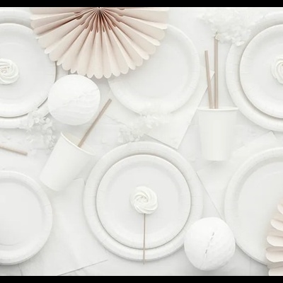 Mesa com decoração em branco e bege com pratos de papel, copos e palhinhas, pirulitos e lanternas de papel