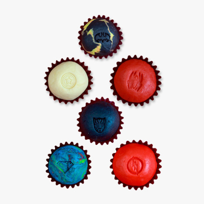 Doces coloridos com símbolos de super-heróis em forminhas vermelhas
