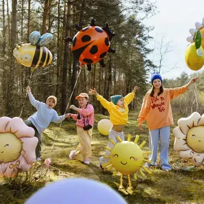 Crianças com balões de hélio de animais e flores em bosque