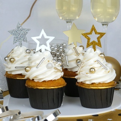 Quatro cupcakes decorados com creme branco, esferas prateadas e douradas, e toppers de estrela em glitter e metalizados.