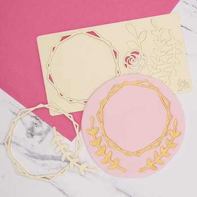 Moldes decorativos em madeira e papel rosa sobre superfície mista