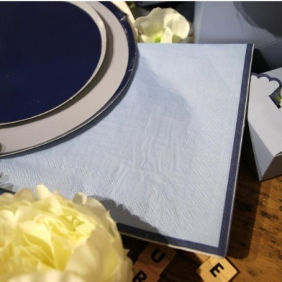 Guardanapo de papel azul claro com borda azul escura e flor amarela