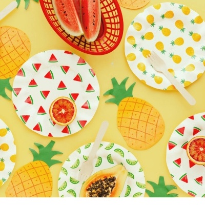 Pratos de papel, talheres de madeira e frutas frescas com decoração de ananás