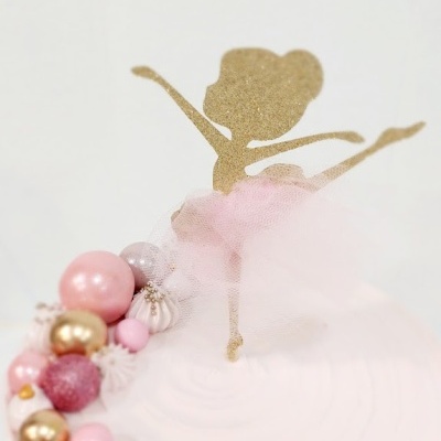 Bolo branco com topper de bailarina dourada com saia de tule cor-de-rosa e esferas decorativas no topo