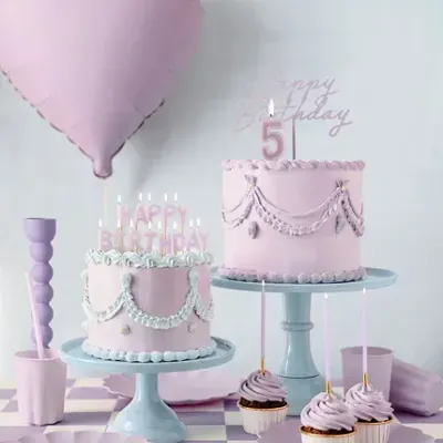 Mesa com bolos decorados em lilás, balão coração lilás, pratos e copos em tom lilás