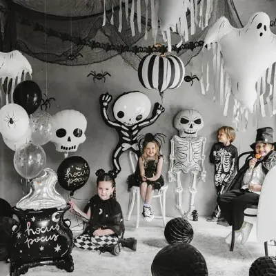Decoração de Halloween com crianças vestidas de esqueleto e mago, balões e fantasmas infláveis