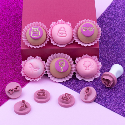Bolachas decoradas com temas femininos em forminhas sobre fundo colorido glitter