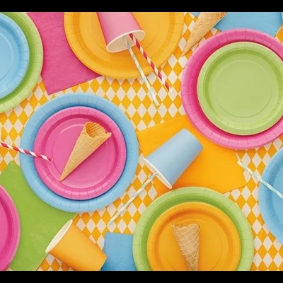 Conjunto colorido de pratos e copos descartáveis sobre superfície geométrica amarela e branca