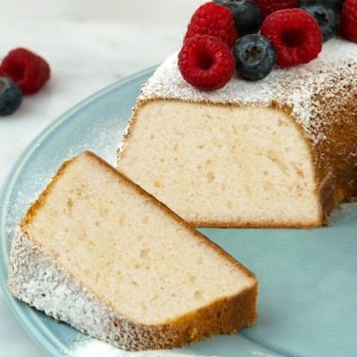 Bolo branco com açúcar em pó e frutos vermelhos num prato azul
