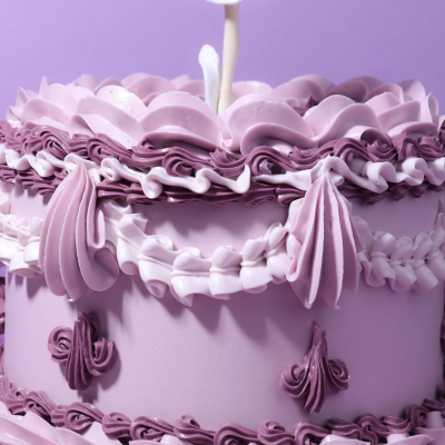 Bolo decorado com glacê lilás e branco com desenhos em ondas e folhagens