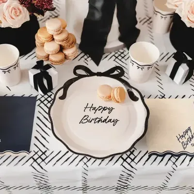 Mesa de aniversário com decoração preta e branca, flores cor de rosa e macarons.