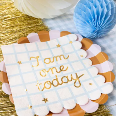 Guardanapos decorativos com texto dourado sobre pratos e decoração em azul, branco e dourado