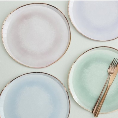 Conjunto de quatro pratos coloridos pastel com bordas douradas e talheres dourados.