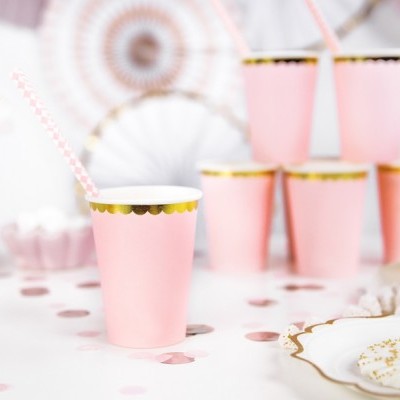 Copos cor-de-rosa com borda dourada e canudo numa mesa decorada