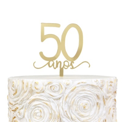 Topo de bolo dourado com o texto 50 anos sobre bolo branco decorado com padrões em espiral