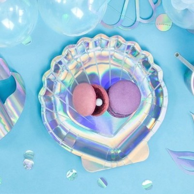 Prato em formato de concha iridescente com dois macarons, decoração azul com balões e itens pastel