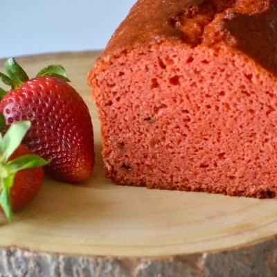 Bolo vermelho fatiado com morangos em tábua de madeira