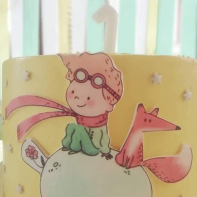 Bolo amarelo decorado com ilustração de menino e raposa na lua, com vela número 1