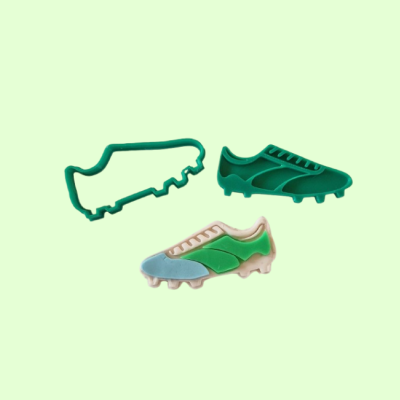 Dois moldes de silicone e um sapato de futebol em fundo verde claro