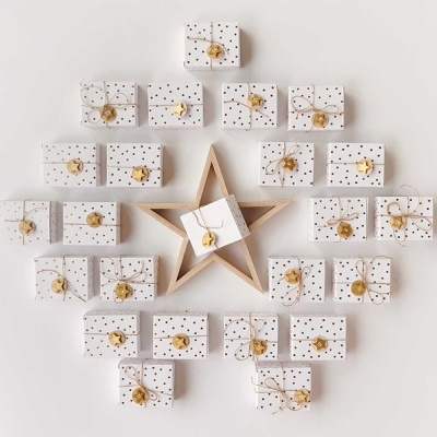 Caixas de presente brancas com pontos dourados e sinos dispostas em forma de árvore e estrela